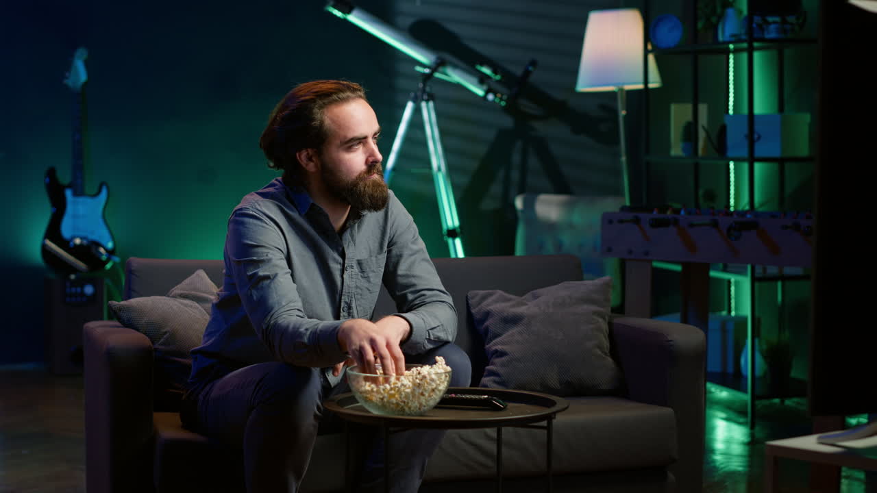 hombre en casa en el sofá agarrado por una película interesante mostrada en la pantalla de televisión