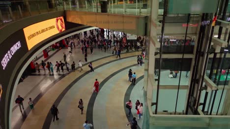 crowded mall interior with elevators and escalators