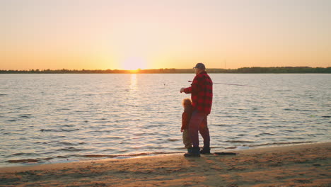 Ruhiger-Sonnenuntergang-Am-Flussufer-Großvater-Und-Enkel-Angeln-Möwen-Fliegen-Am-Horizont