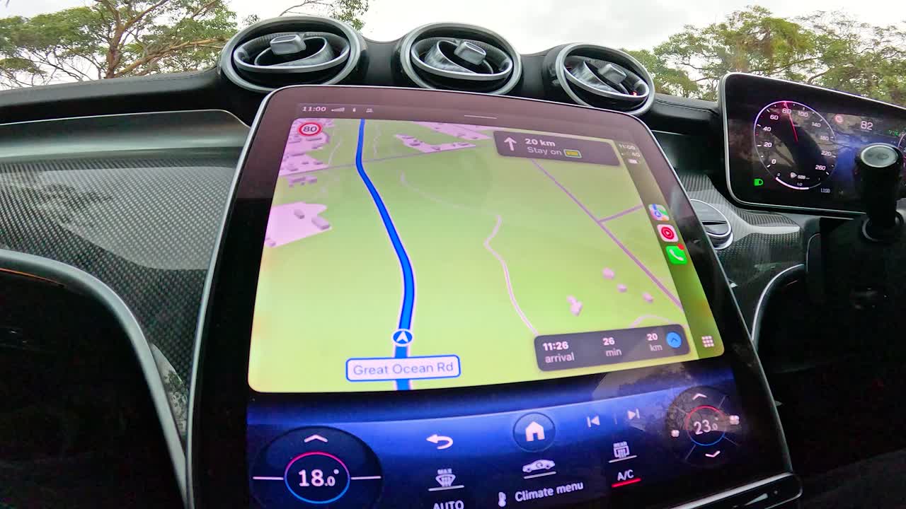 A car journey along the Great Ocean Road, showcasing lush landscapes and a modern GPS interface inside the vehicle