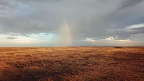 Drohnenaufnahme-Eines-Regenbogens-In-Der-Ferne-Auf-Einer-Sehr-Trockenen-Namibischen-Schaffarm