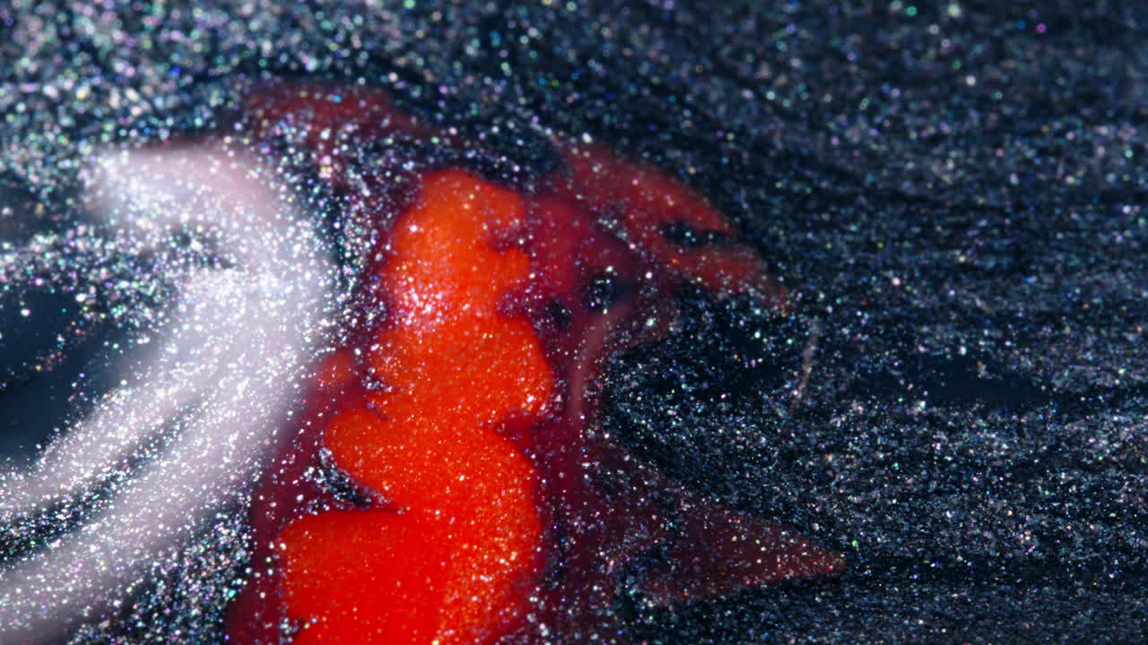 Red and black substances swirling and merging in a close-up, glittery texture and abstract look