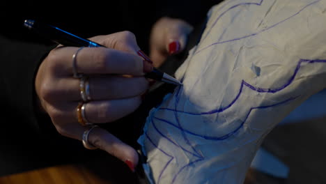joven zapatera dibujando un diseño campestre estampado en un zapato antiguo en un taller antiguo, de cerca