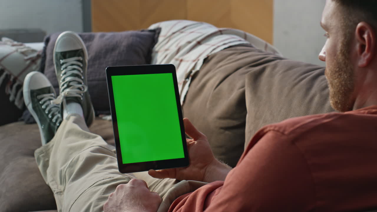 Man holding mockup tablet sitting comfortable apartment sofa closeup. Young guy