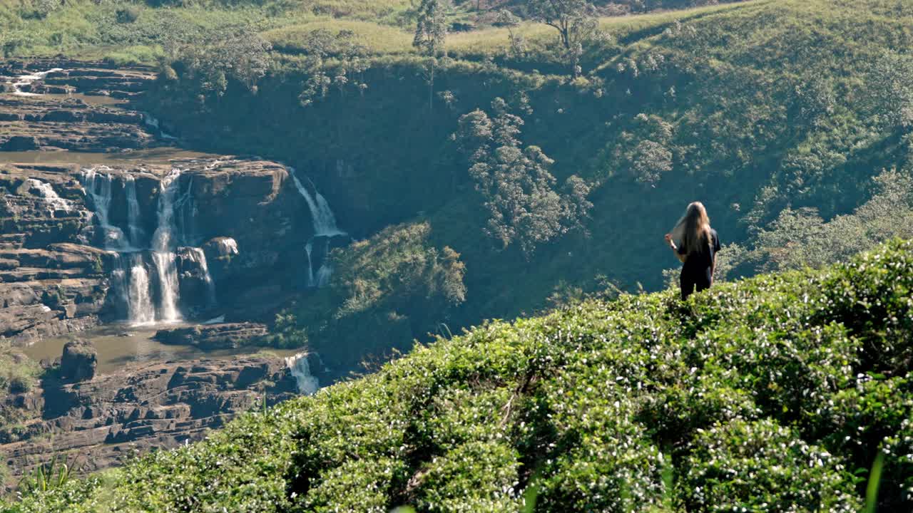 Footage of a woman walking through lush tea plantations at Saint Clair’s Falls in Nuwara Eliya, Sri Lanka.