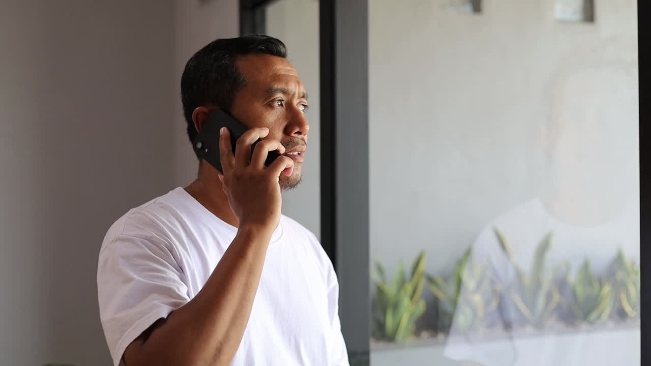 Asian man with phone call for talking, gossip and communication with digital contact near window at home