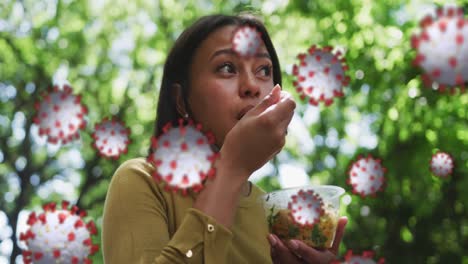 Animation-of-covid-19-cells-over-woman-eating-lunch-in-city-with-face-mask