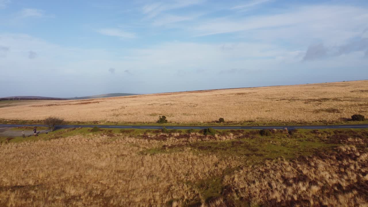 dron aéreo descendente sobre una hermosa carretera rural con un cielo azul nublado en exmoor reino unido 4k