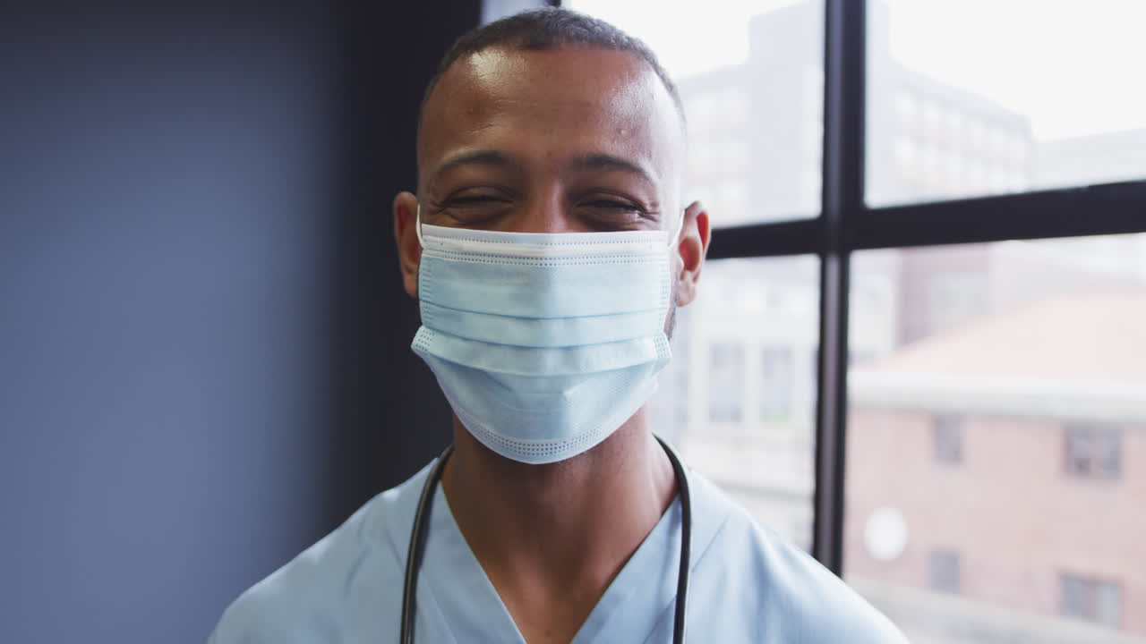 retrato de un médico de dos razas que lleva una máscara facial mirando a la cámara y sonriendo