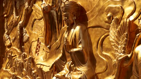 intricate gold sculpture depicting taoist figures