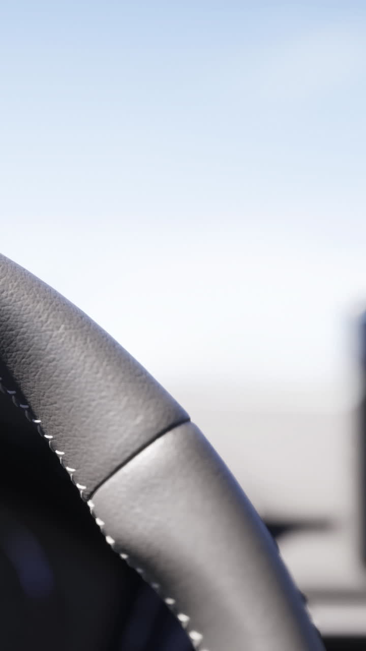 Primer plano de un volante con un salpicadero de fondo mientras se conduce.