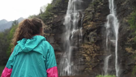 Woman-in-foreground-admiring-the-natural-steep-Acquafraggia-torrent-in-Valchiavenna,-Italy