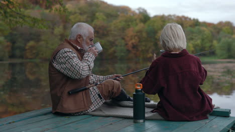grandfather and child fishing on a lake pier in autumn