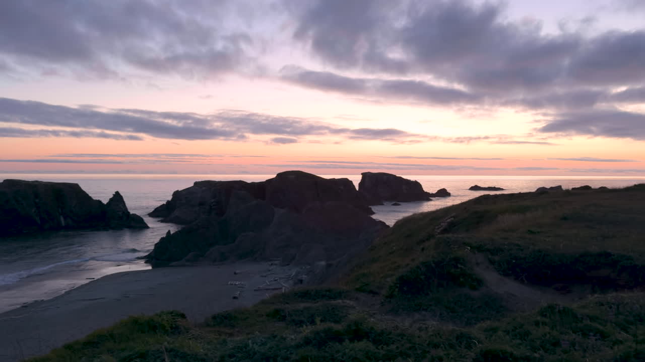 Dramatic sunset on Oregon Coast with sea stacks, panning shot. Silhouetted rocks and beach in Bandon, Oregon.