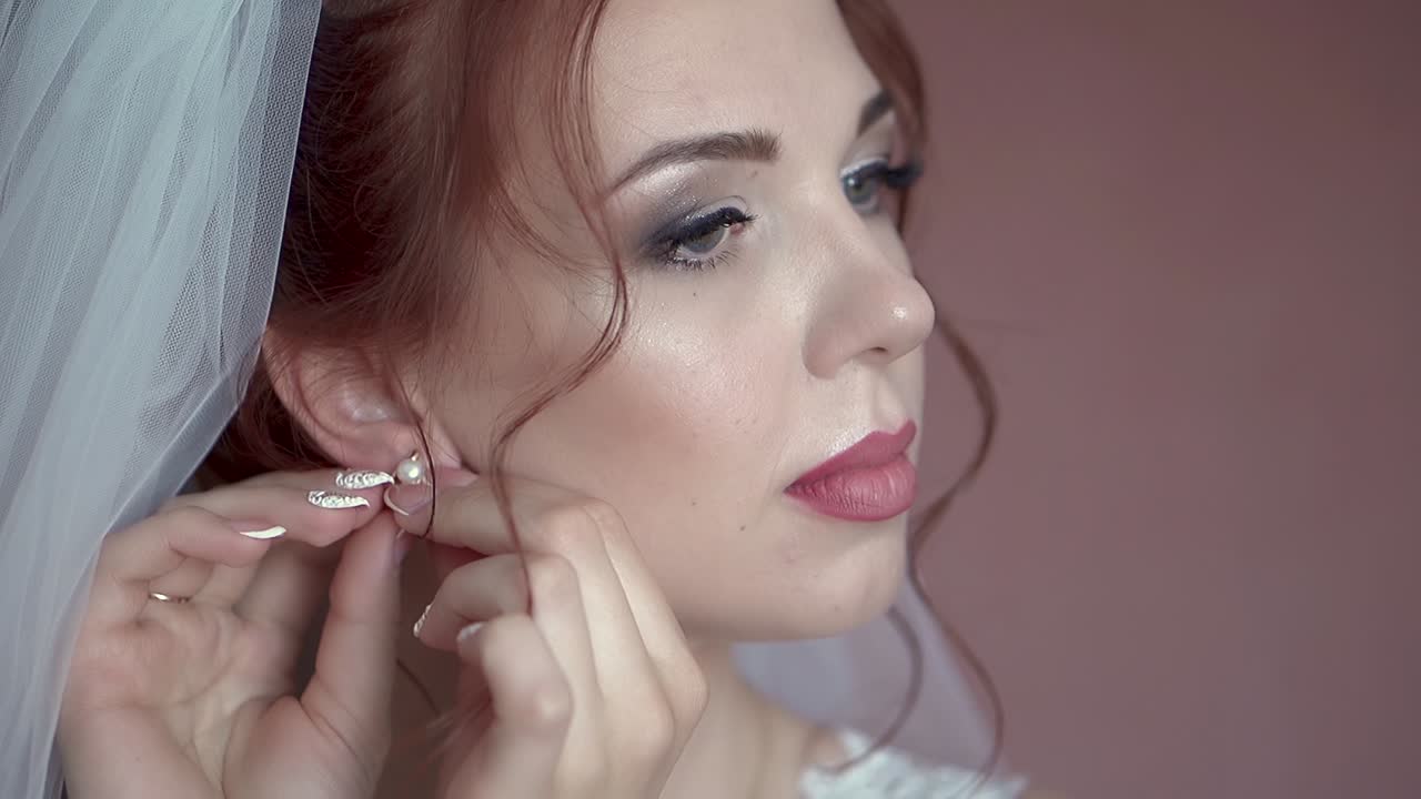 Bride is putting on earrings close-up slow motion