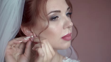 Bride-is-putting-on-earrings-close-up-slow-motion