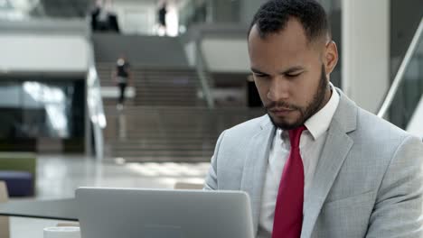 focused young man wearing suit working with laptop at cafe.