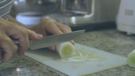 detail of a woman cutting a leek into rounds using a sharp knife