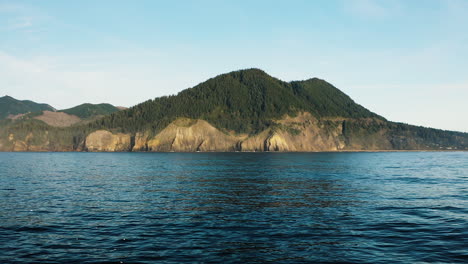 Aerial-push-in-towards-forested-peak-overlooking-Pacific-Ocean,-Oregon-Coast