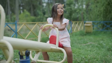 a pregnant mother and her young daughter enjoy playful time together at a playground in the park, surrounded by trees and greenery