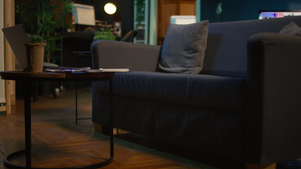 Stylish empty apartment loft with a comfortable couch and smart tv in the living room, modern space with decorations and funky neon lights. Studio with a coffee table and home theatre setup.