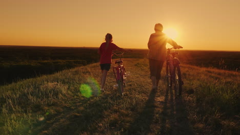 Una-Anciana-Camina-Con-Su-Nieta-En-Bicicleta-Al-Atardecer-2