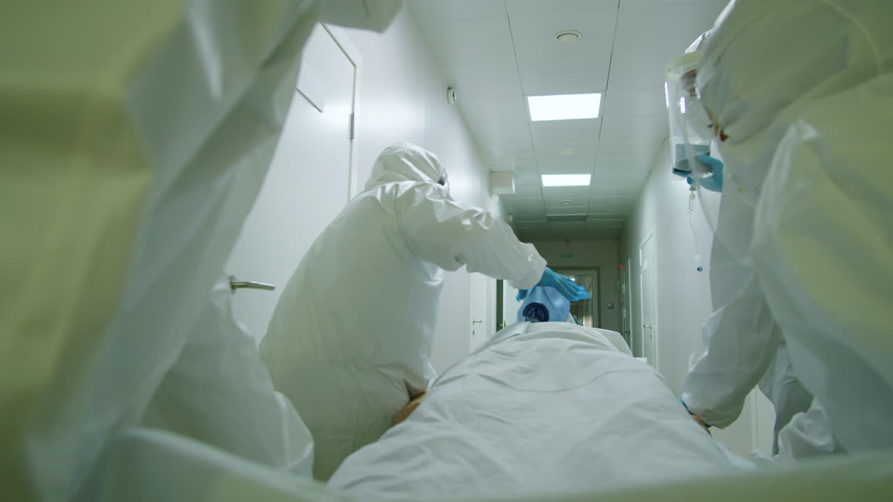 médicos en trajes de protección transportando pacientes en camilla