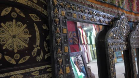 close up view of beautifully decorated with filligree work on the mirror frames placed in an antique shop by the side of a road on a busy morning.