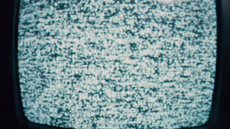 old tv with static on display, blinking in a dark room