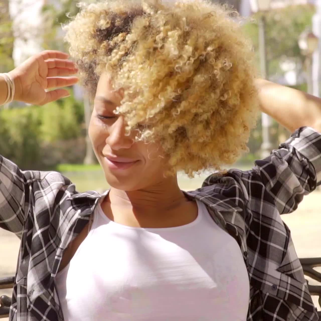 mujer joven sonriente relajándose en un banco bajo el sol