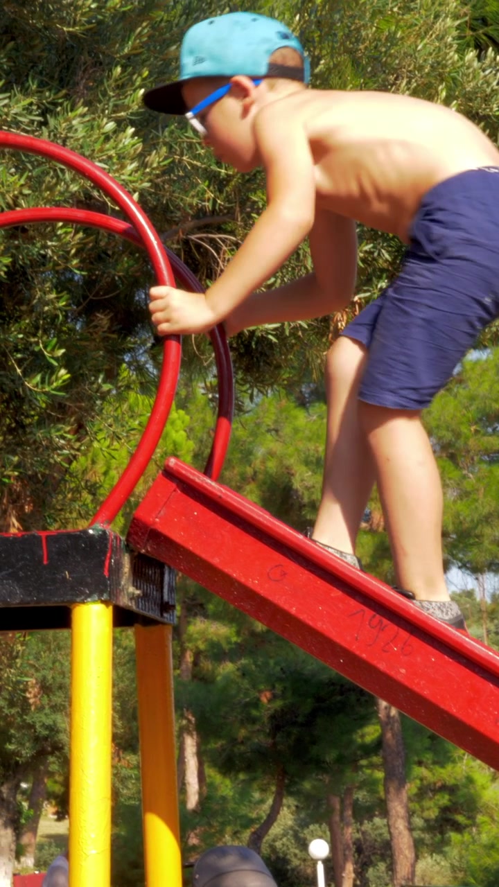 Actividades infantiles al aire libre. Niño subiendo por un tobogán en un parque infantil