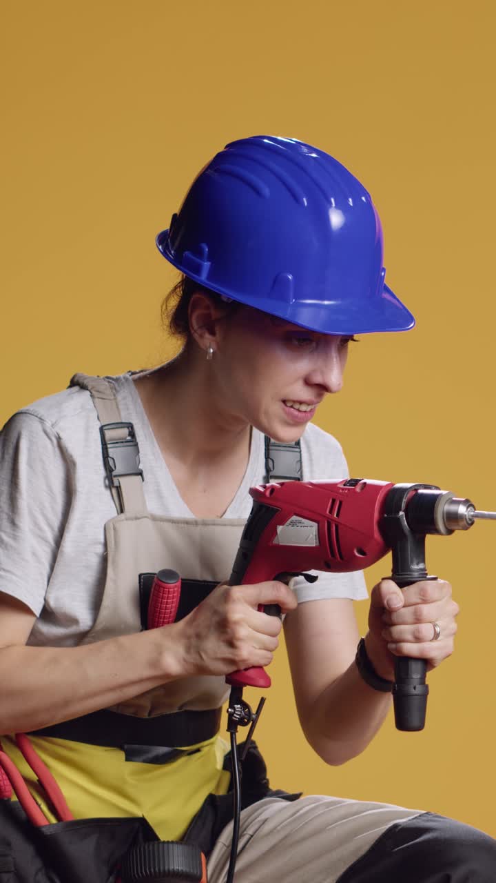 Vertical video: Strong handywoman drilling nails with power drill gun