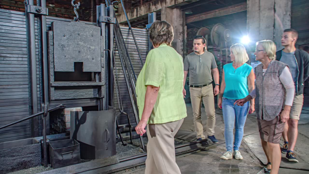 Arc shot. Tourists listening to Ironmaking Museum tour guide. Ravne na Koroskem