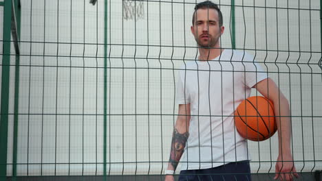 man with basketball behind a fence