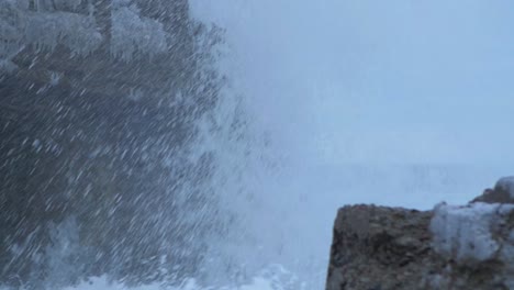 Big-stormy-waves-breaking-against-abandoned-seaside-fortification-building-ruins-at-Karosta-Northern-Forts-in-Liepaja,-slow-motion-medium-closeup