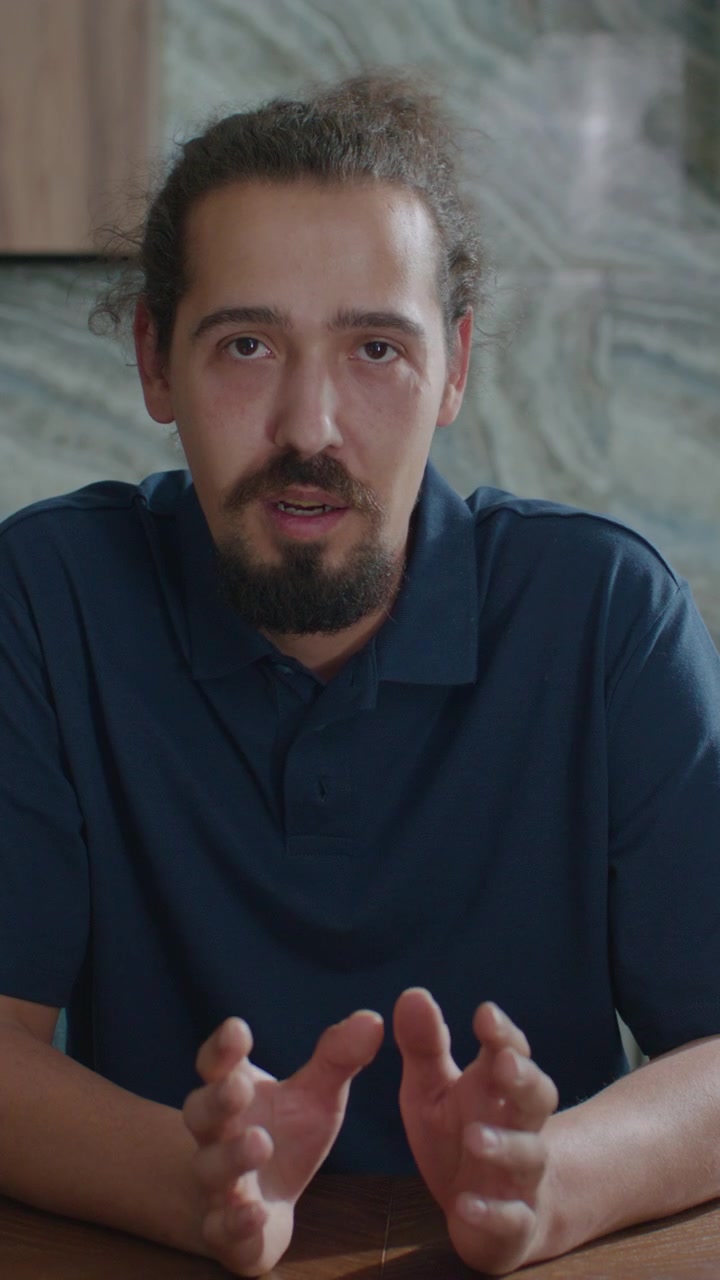 Verticale di giovane uomo che saluta e parla in camera tramite videochiamata