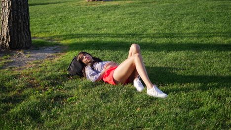 beautiful young hispanic woman in a daydream in a grass public park field watching the clouds