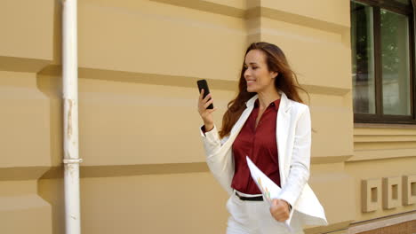 Mujer-De-Negocios-Alegre-Llama-Video-En-Línea-En-Un-Teléfono-Móvil-Al-Aire-Libre