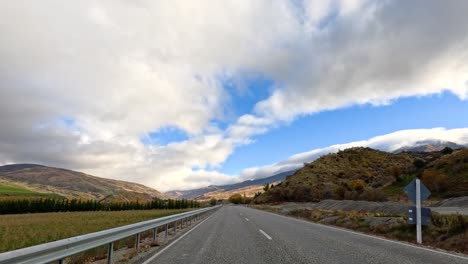 a 45-second drive through wanaka's picturesque roads, showcasing vibrant autumn colors under dynamic cloud formations and clear blue skies