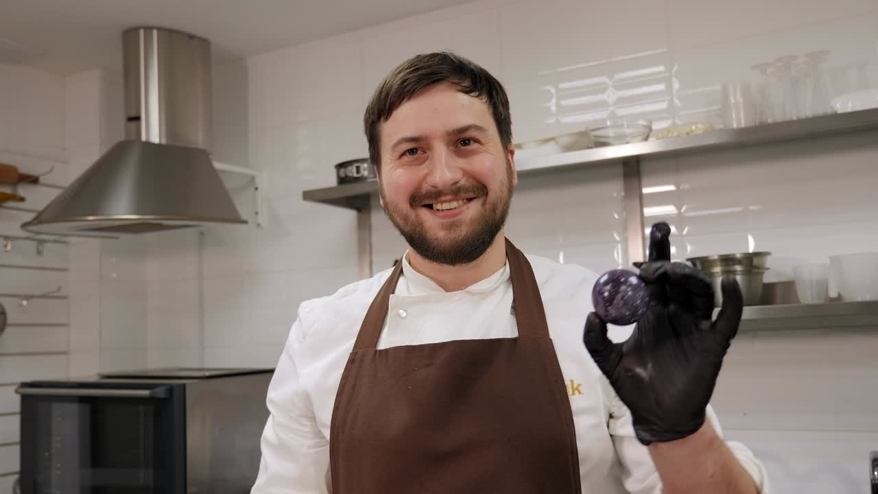 un chef de pastelería tiene un caramelo de chocolate hecho a mano o praline en una pastelería.