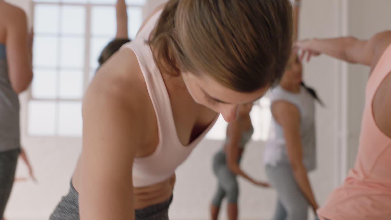 요가 수업 피트니스 스튜디오 그룹 명상에서 유연한 신체를 운동하는 건강한 라이프스타일을 즐기는 삼각형 포즈를 연습하는 매력적인 여성