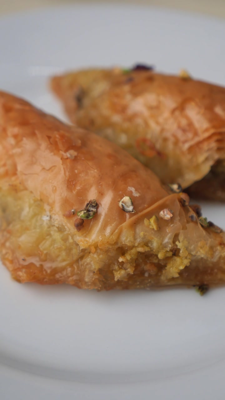 Close-up of Traditional Golden Baklava with Pistachios on a White Plate