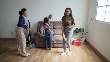 happy asian family stacking hands and cheering before cleaning home doing housework together