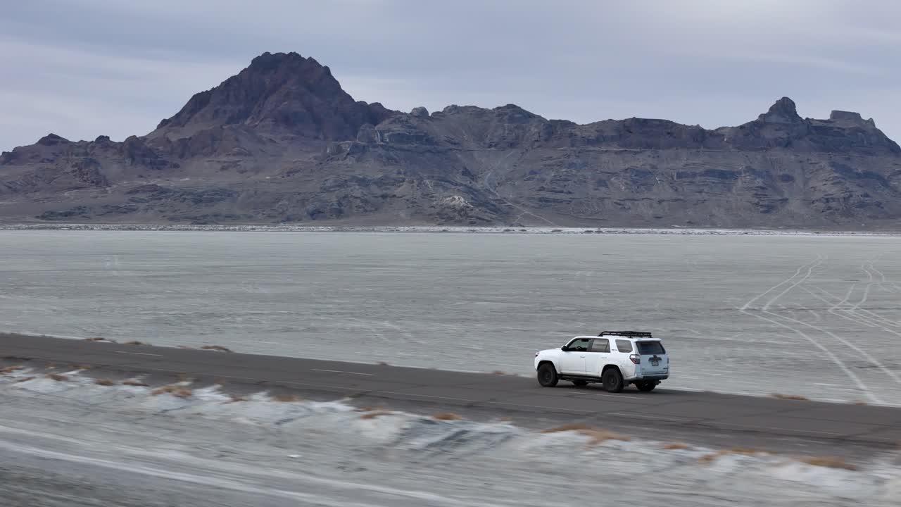 Tracking Drone Shot of White SUV Vehicle Moving on Road in Desert Landscape