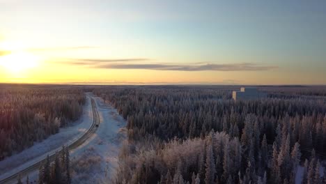 Aéreo,-Seguimiento,-Tiro-De-Drone,-Con-Vista-A-Un-Automóvil-En-Una-Carretera-Congelada,-En-Medio-Del-Bosque-Boreal,-Al-Atardecer,-En-Una-Tarde-Soleada-De-Invierno,-En-Gakona,-Alaska,-Estados-Unidos