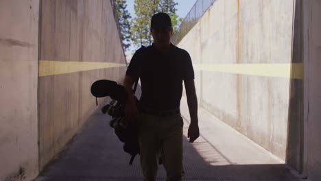 a golfer carries his clubs as he walks towards the camera