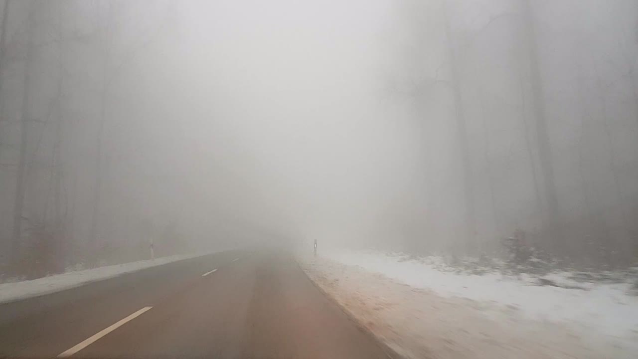 독일 산속의 눈 덮인 안개 낀 길에서 빠르게 운전하다