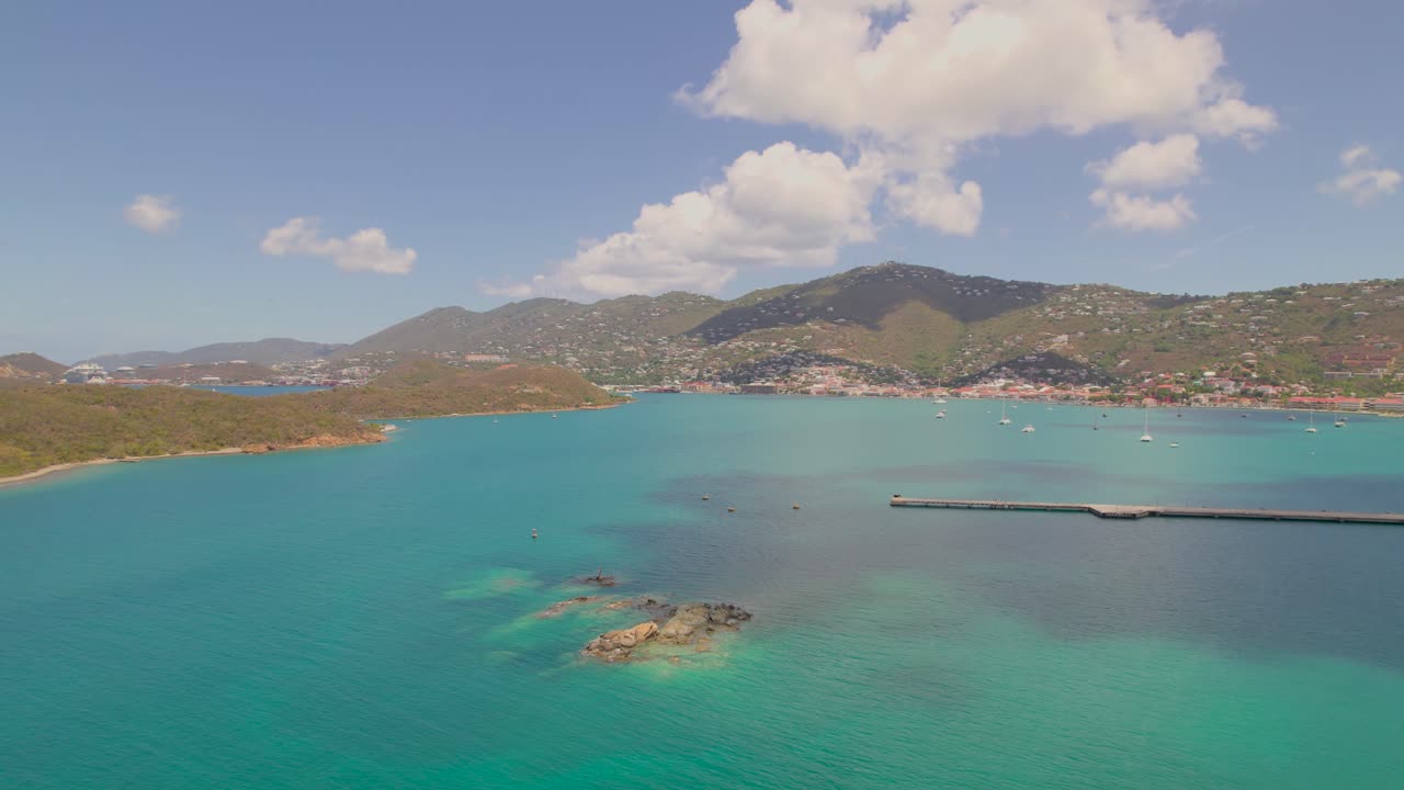 Riprese aeree di un lago turchese sereno con montagne sullo sfondo sotto un cielo azzurro brillante, Saint Thomas, Isole Vergini Americane.
