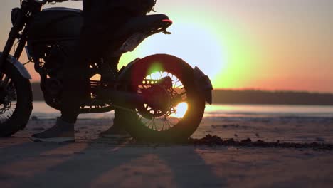 El-Motociclista-Empuja-En-El-Lugar-Con-La-Rueda-Trasera-Con-La-Puesta-De-Sol-Al-Fondo