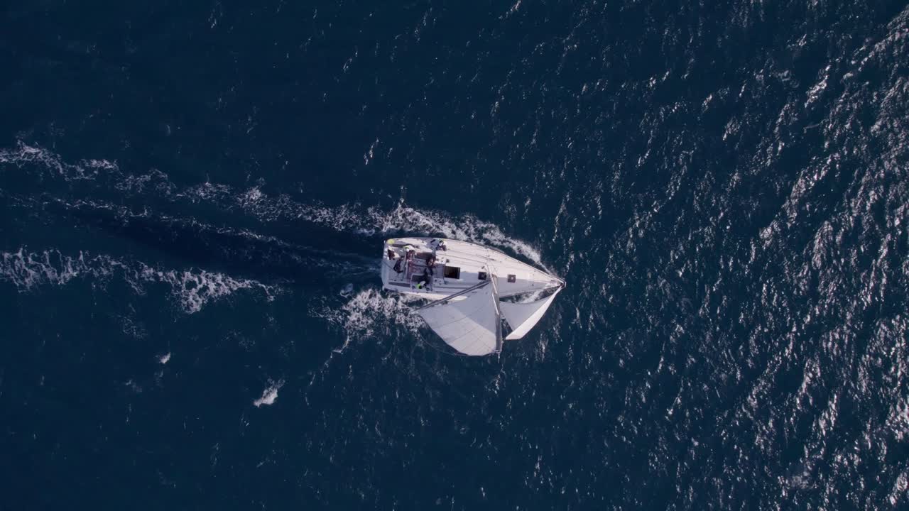 Vista drone di una barca a vela che galleggia su acque calme e di un blu intenso